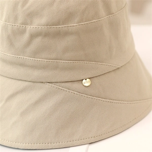 Detail of light khaki bucket hat showing fine woven fabric and gold metal brand buckle