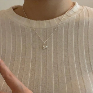 Close-up of a 925 sterling silver irregular V-shaped pendant necklace worn on a person