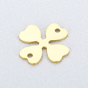 Close-up of golden clover-shaped metal pendant with double holes for jewelry making