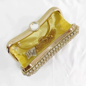 Detail view of gold evening clutch bag with sparkling rhinestones and crystal clasp