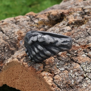 Retro stainless steel handshake ring with a vintage oxidized finish on rustic wood bark