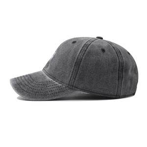 Detail view of washed cotton fabric texture and circular embroidery on dark grey baseball cap