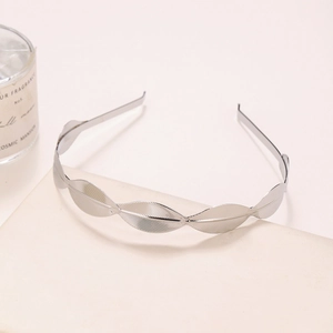 Detail shot of silver metal leaf headband on a minimalist display with a candle