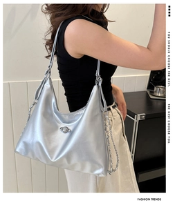 Detail of silver metallic hobo bag featuring a metal planet logo and chain strap
