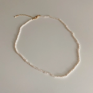 Detail of freshwater pearl necklace featuring gold lobster clasp and adjustable chain extender