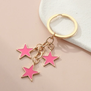 Close-up of golden star keychain with pink enamel charms on a ceramic plate