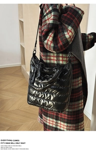 Close-up of black quilted puffer tote bag with glossy finish and thick padded texture