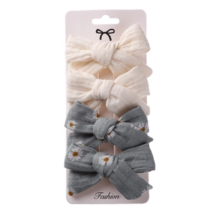 Detail of 4-piece bow hair clips set featuring beige and blue daisy floral linen fabric