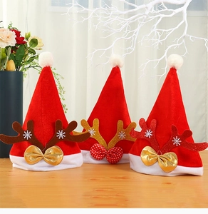 Detailed view of red velvet Christmas hats with antlers and decorative bows on wood