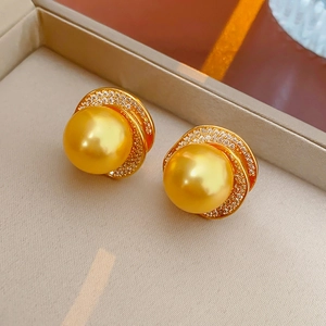 Close-up of vintage golden pearl earrings with zircon stones in a jewelry box
