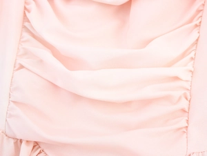 Dettaglio ravvicinato del tessuto in chiffon plissettato rosa con texture morbida e fine