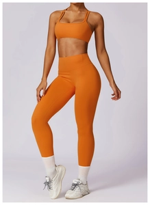 Detail view of bright orange yoga set featuring high-waisted leggings and sports bra