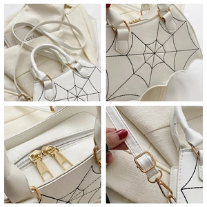 Detail of gothic white bat-shaped handbag with spider web embroidery and gold hardware