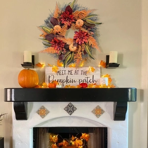Gros plan d'une couronne d'automne avec citrouilles et feuilles d'érable sur une cheminée