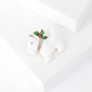 Close-up of a white enamel Scottish Terrier dog brooch with festive holly berry details