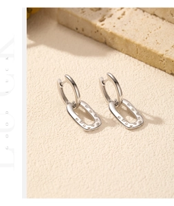 Macro detail of geometric silver earrings with crystals on a textured stone background
