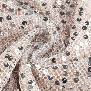 Macro shot of silver sequins on pink mesh fabric with elegant drape and shimmer