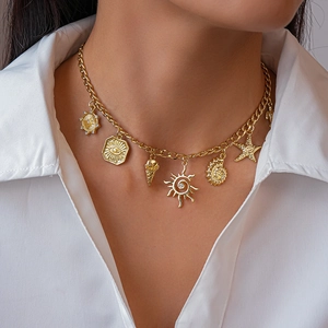 Detail of gold chunky chain necklace with starfish, shell, and sun charms on a model