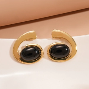 Close-up of vintage gold metal geometric oval earrings with black resin inlay detail