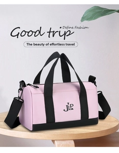 Pink nylon duffel bag with JLP logo and black straps on a wooden display stand
