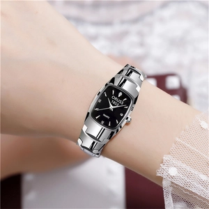 Detail view of the silver tonneau-shaped watch with black dial on a female wrist
