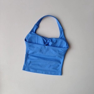 Top yoga blu con allacciatura al collo e lati a coste su sfondo grigio chiaro