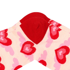 Macro shot of pink cotton knit socks featuring vibrant red and dark pink heart patterns