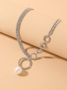 Macro shot of asymmetrical silver necklace featuring rhinestones and a large pearl