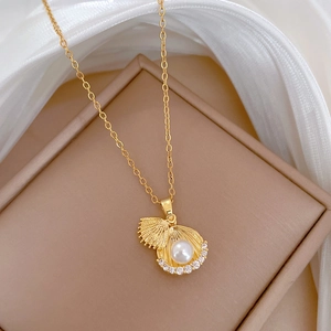 Détail d'un collier avec pendentif coquillage doré, perle blanche et cristaux brillants