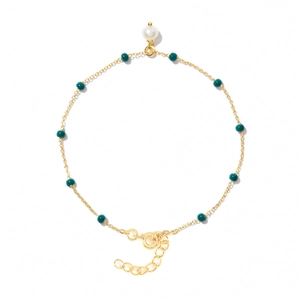 Detailed close-up of gold chain bracelet with green beads and a white pearl charm