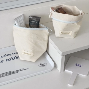 Detailed shot of cream-colored cosmetic pouches in zipper and drawstring styles