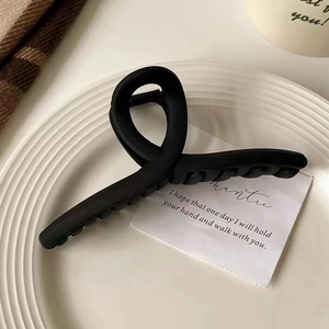 Détail d'une grande pince à cheveux noir mat au design torsadé sur une assiette en céramique