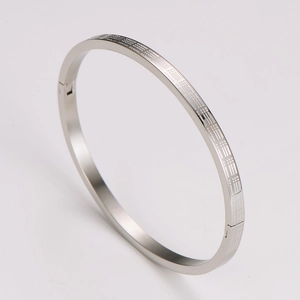 Detailed view of silver metal bracelet with intricate geometric plaid pattern engraving
