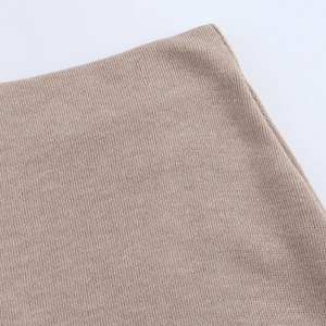 Macro detail of soft apricot knit fabric showing fine texture and quality stitching