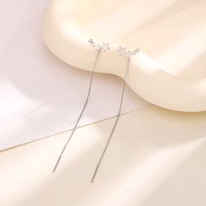 Macro detail of silver long star ear threaders with zircon embellishments on tray