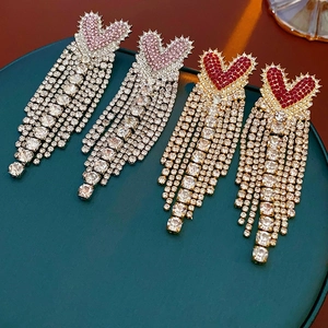 Detail view of heart tassel earrings in gold with red crystals and silver with pink stones