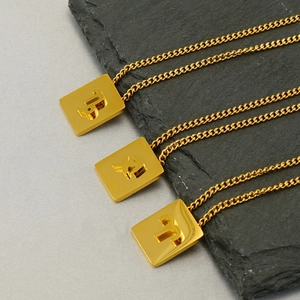 Detailed macro view of gold square zodiac necklaces featuring Capricorn and Aries symbols