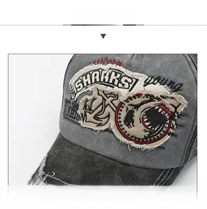 Detail of dark gray washed cotton baseball cap with shark embroidery and distressed brim