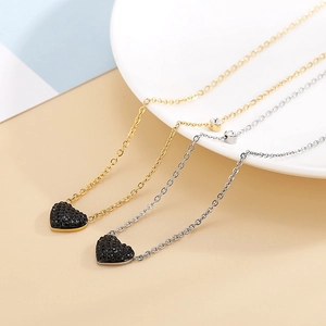 Détail des colliers dorés et argentés avec pendentifs cœur noir sertis de strass
