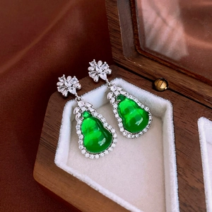 Macro detail of silver needle earrings with green resin gourd and zircon floral studs