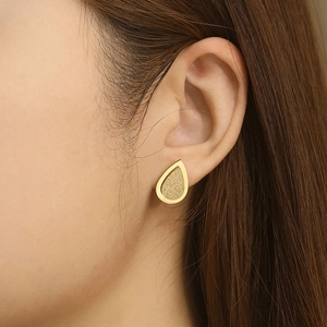 Close-up of elegant gold teardrop earrings with a textured matte finish on a female model