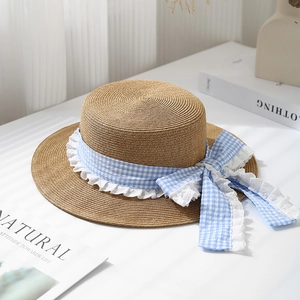 Detailed straw weave texture on flat top summer hat with blue checkered bow and lace trim