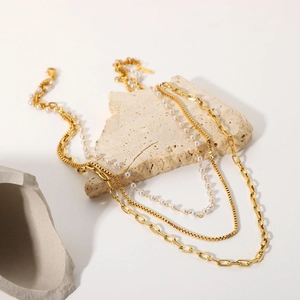 Détail du collier triple rang en acier inoxydable doré 18K avec perles sur socle en pierre