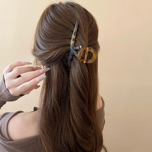 Detail of a large amber tortoiseshell hair claw clip securing long brown hair in a bun