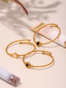 Detailed shot of gold twisted rope bracelets with black and white shell round inlay charms