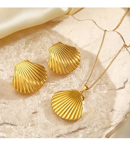 Golden shell necklace and earrings set on wavy glass with champagne silk background