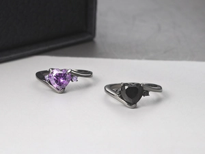 Macro shot of black gold bypass rings with heart-shaped purple and black zircon stones