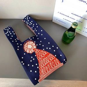Détail du sac en maille bleu marine avec motif de bonnet orange et texture de flocons