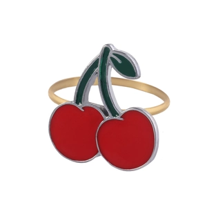 Close-up of a red and green cherry enamel napkin ring with a polished gold metal band