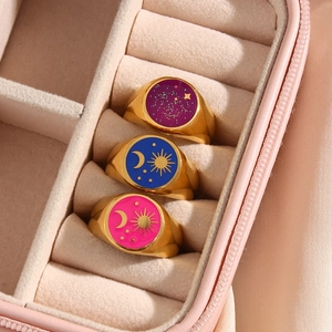 Set di anelli dorati con sole e luna e smalto celeste viola e blu in un portagioie beige